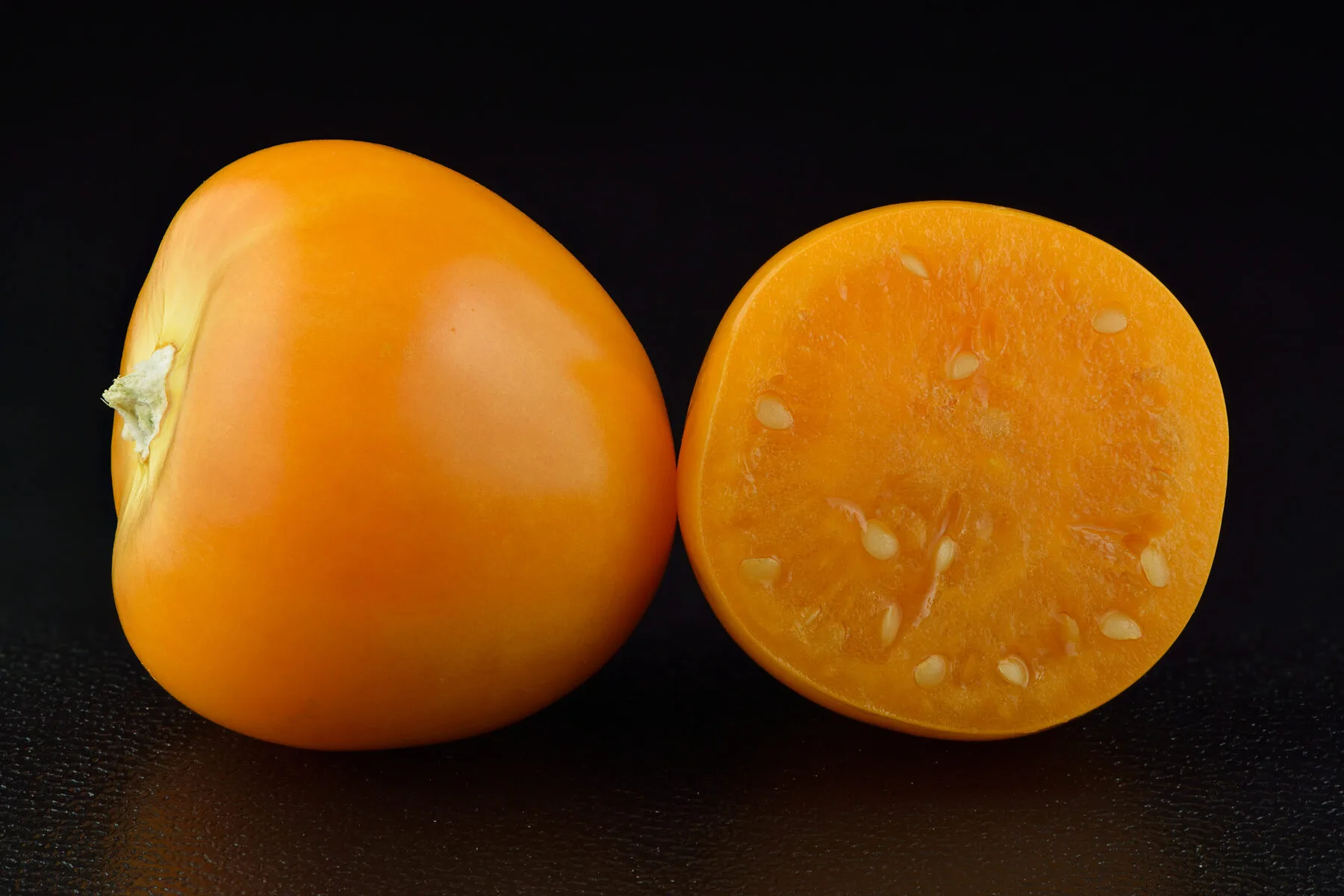 Orange Andenbeere ganz und halbiert, mit vielen kleinen Samen im Fruchtfleisch
