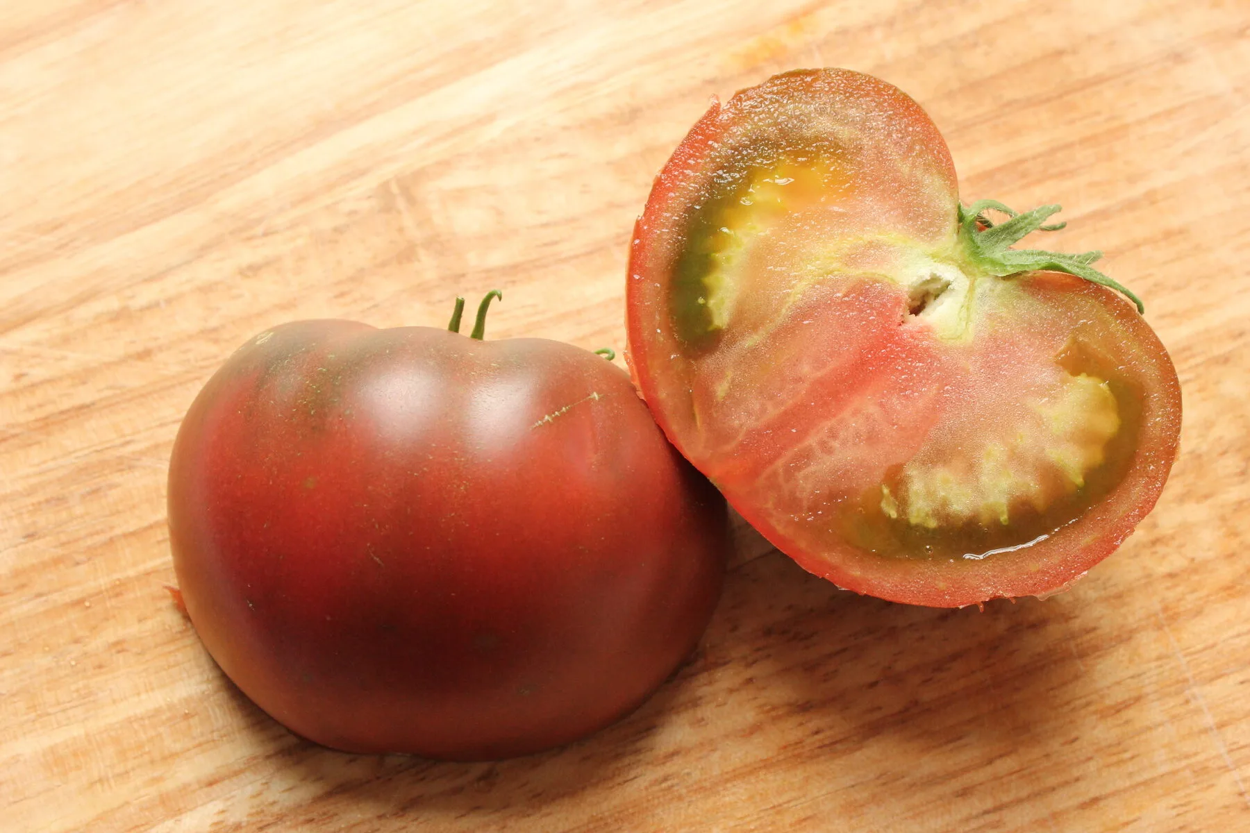 Aufgeschnittene dunkle Fleischtomate mit sichtbaren Samen in gelartigen Kammern